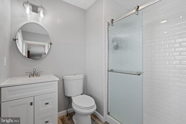 bathroom with vanity, hardwood / wood-style flooring, a shower with door, and toilet