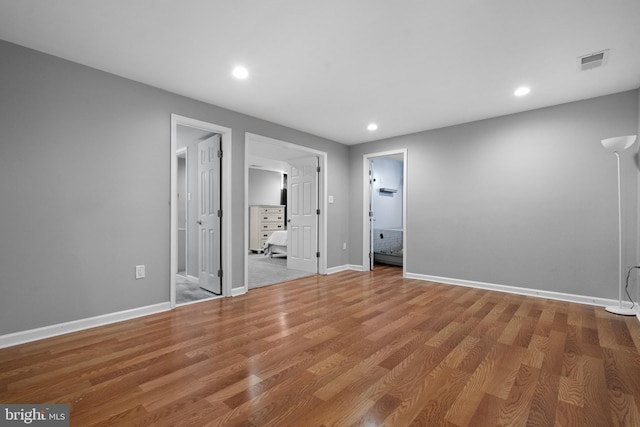 unfurnished bedroom featuring ensuite bath and wood-type flooring