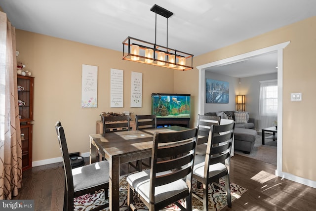 dining area featuring dark wood-type flooring and an inviting chandelier