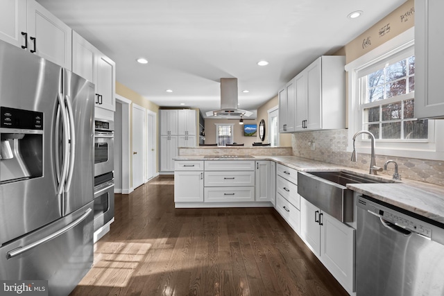 kitchen featuring island range hood, stainless steel appliances, kitchen peninsula, and white cabinets