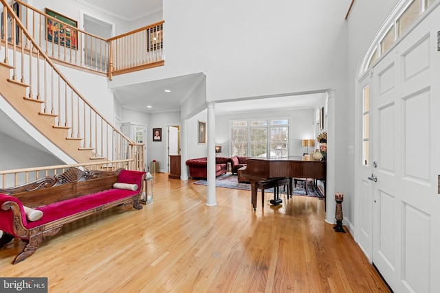 entrance foyer featuring a towering ceiling, ornamental molding, hardwood / wood-style floors, and ornate columns