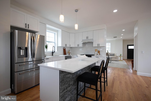 kitchen with stainless steel refrigerator with ice dispenser, sink, white cabinetry, pendant lighting, and backsplash