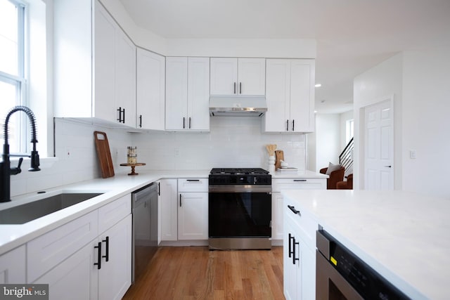 kitchen with range with gas cooktop, dishwasher, sink, white cabinets, and light hardwood / wood-style flooring