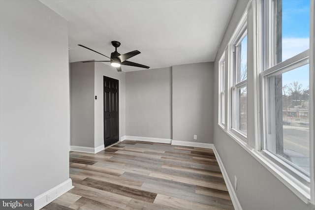 unfurnished room featuring a ceiling fan, baseboards, and wood finished floors