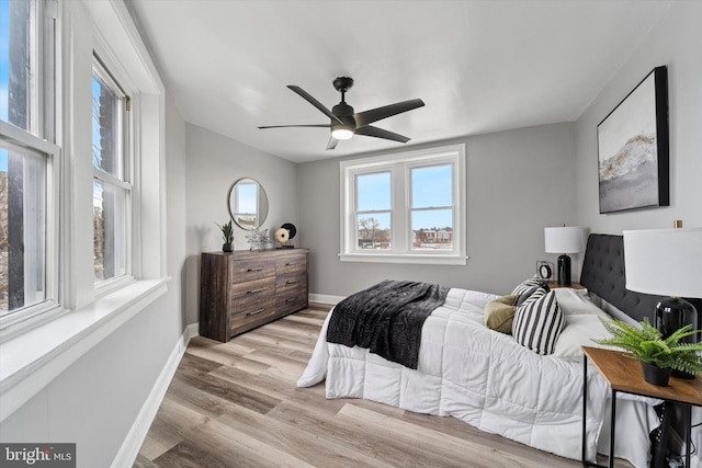 bedroom with light wood finished floors, ceiling fan, and baseboards