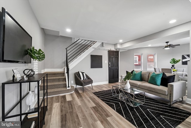 living area featuring recessed lighting, wood finished floors, stairway, and a barn door