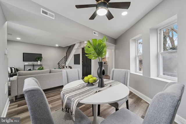 dining area with stairway, baseboards, visible vents, and wood finished floors