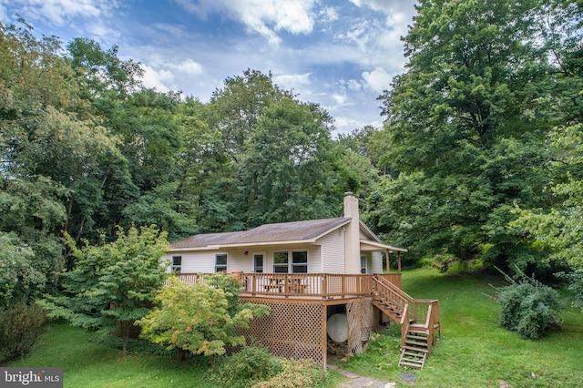 back of property featuring a deck and a lawn