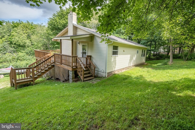 rear view of property featuring a lawn and a deck