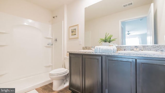 bathroom with hardwood / wood-style flooring, ceiling fan, vanity, a shower, and toilet