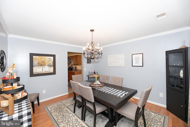 dining area with ornamental molding, a chandelier, and light hardwood / wood-style floors