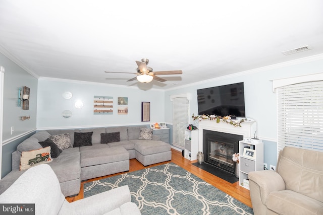 living room with crown molding, ceiling fan, and wood-type flooring