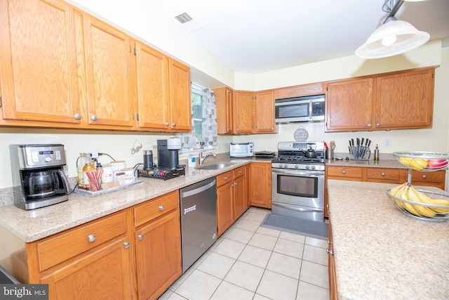 kitchen with appliances with stainless steel finishes, sink, hanging light fixtures, and light tile patterned floors