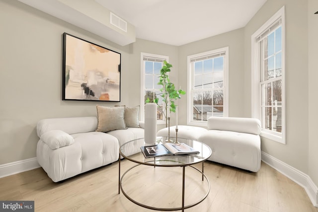 sitting room with light wood finished floors, visible vents, and baseboards