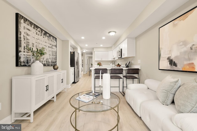 living room featuring light wood-type flooring, baseboards, and recessed lighting