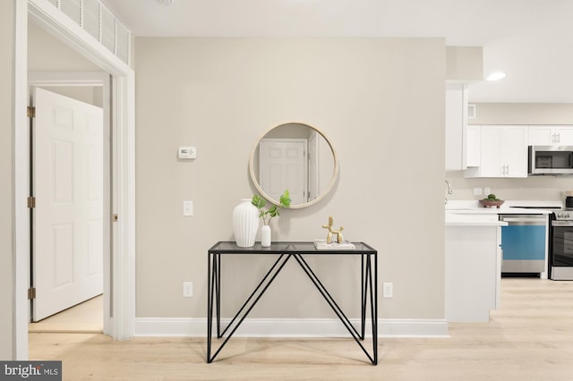 interior space featuring light wood finished floors, baseboards, and a sink