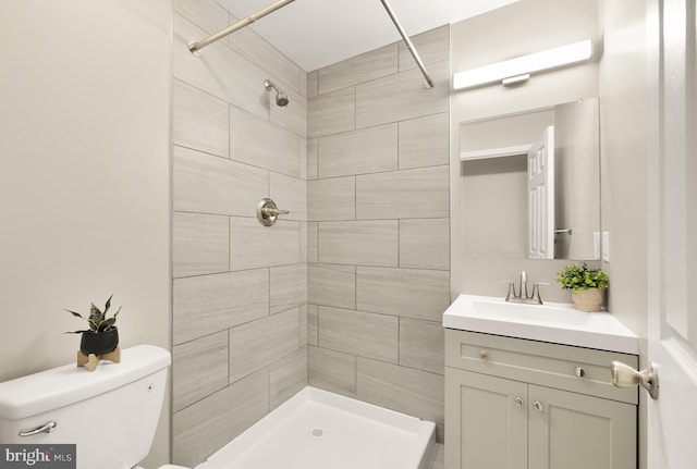 full bath featuring a tile shower, vanity, and toilet