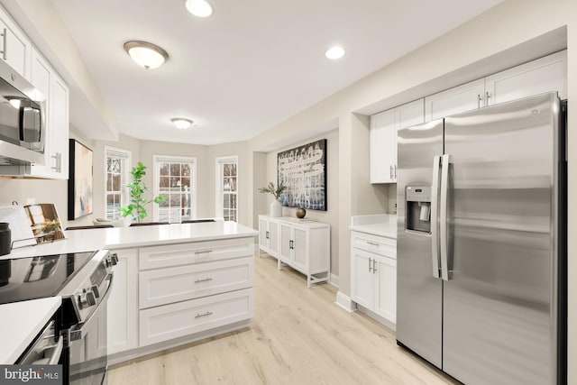 kitchen featuring white cabinets, light wood-style floors, stainless steel appliances, and light countertops