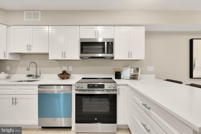 kitchen featuring white cabinetry, visible vents, stainless steel appliances, and a sink