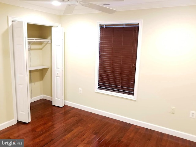 unfurnished bedroom featuring crown molding, dark wood-style flooring, a closet, and baseboards