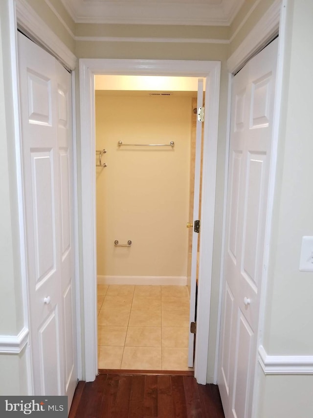 hallway with baseboards, dark tile patterned flooring, and crown molding