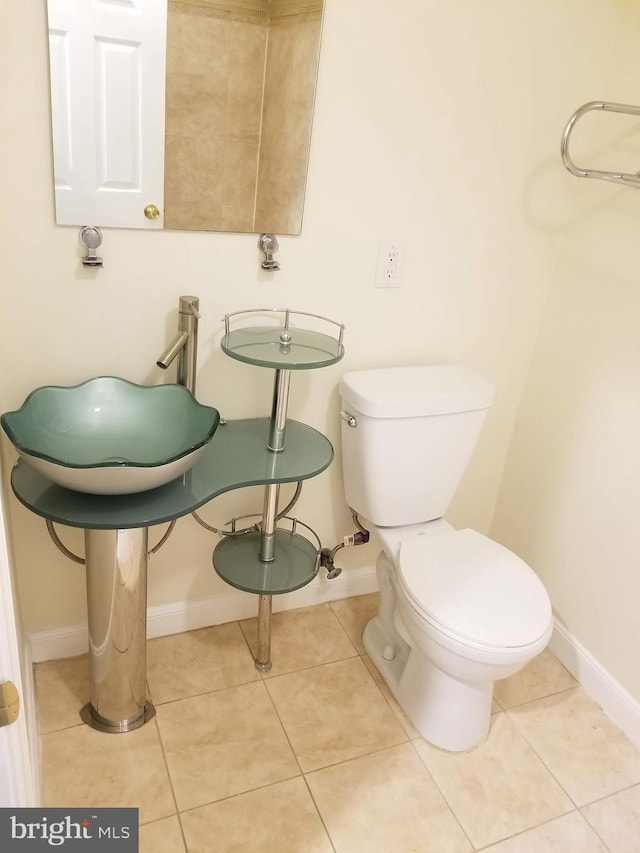 half bathroom featuring toilet, tile patterned flooring, and baseboards