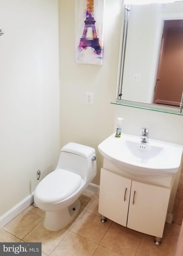 bathroom with toilet, tile patterned flooring, vanity, and baseboards