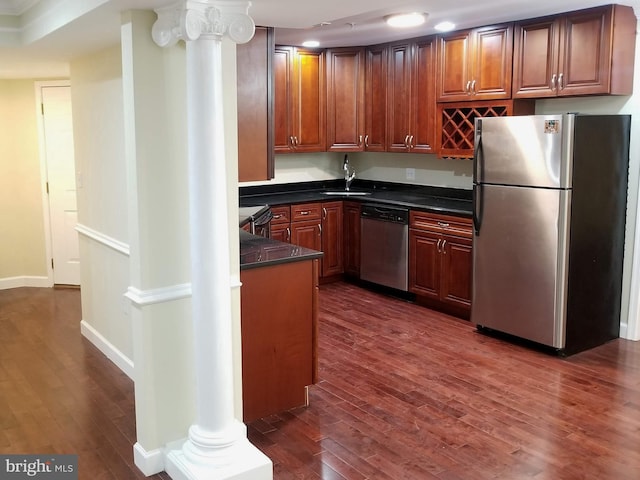 kitchen featuring appliances with stainless steel finishes, dark countertops, ornate columns, and dark wood-style floors