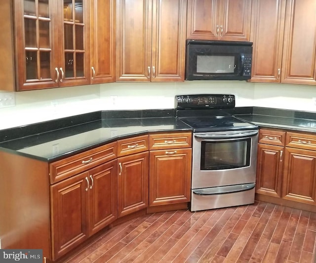 kitchen featuring glass insert cabinets, brown cabinets, dark wood-type flooring, stainless steel electric stove, and black microwave