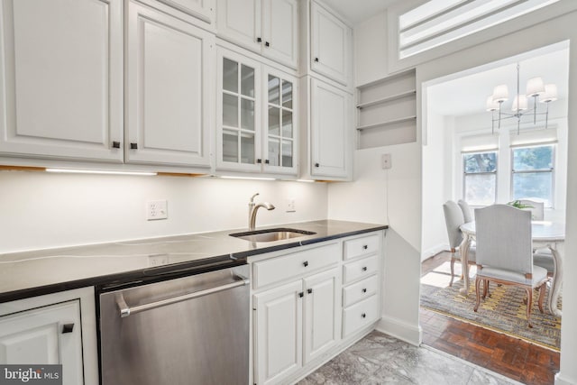 kitchen with dark countertops, white cabinetry, a sink, dishwasher, and baseboards