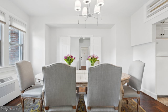 dining room featuring a chandelier, radiator, and baseboards