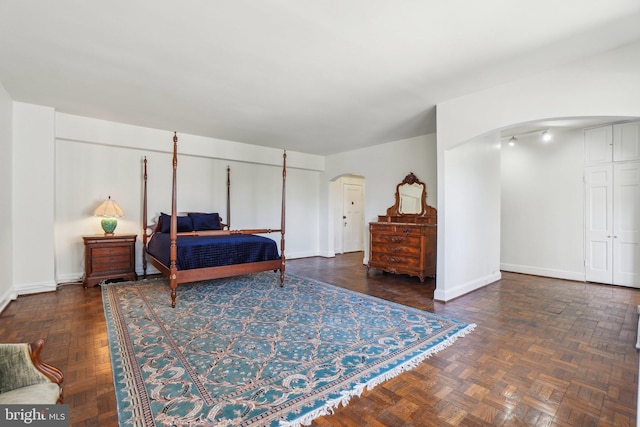 bedroom featuring baseboards and arched walkways