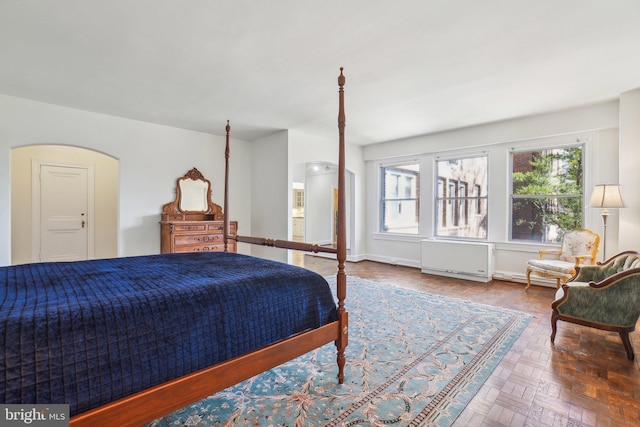 bedroom with radiator, baseboards, and arched walkways