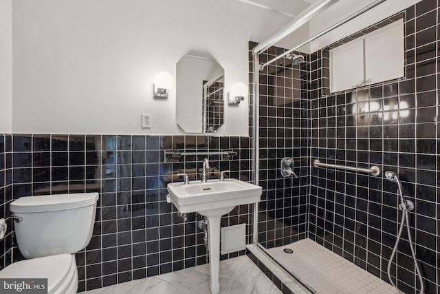 full bath with marble finish floor, tiled shower, toilet, and tile walls