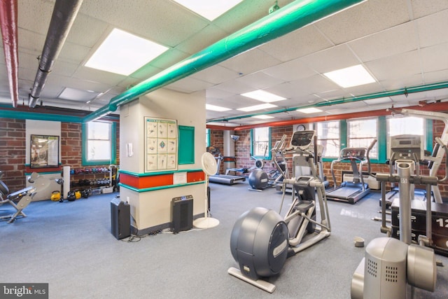 gym with brick wall and a drop ceiling