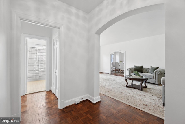 hallway featuring arched walkways and baseboards