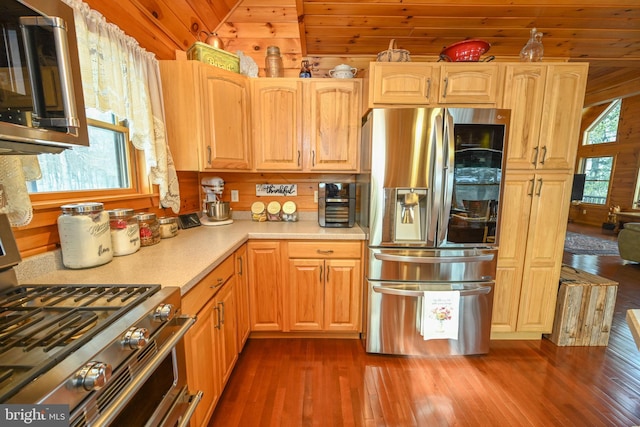 kitchen featuring vaulted ceiling, wooden walls, dark hardwood / wood-style flooring, stainless steel appliances, and wooden ceiling