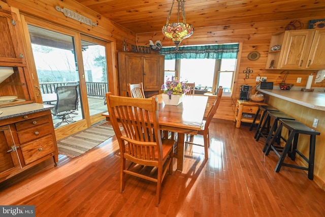 dining room featuring wooden walls, wooden ceiling, and light hardwood / wood-style floors