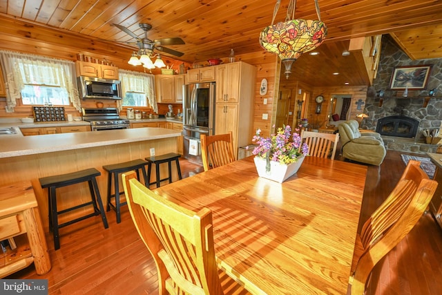 dining space with wood ceiling, plenty of natural light, a fireplace, and light wood-type flooring