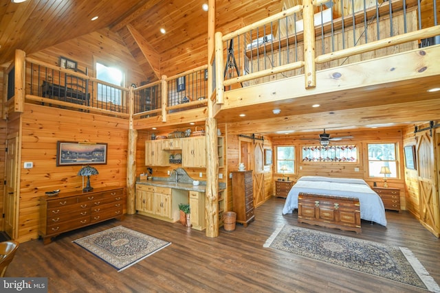 bedroom with a barn door, dark hardwood / wood-style floors, and wood walls