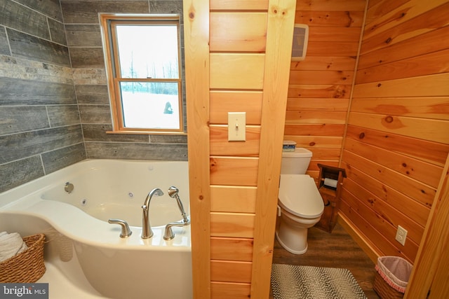 bathroom with toilet, wooden walls, and a bath