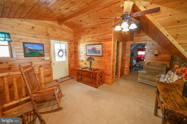 sitting room featuring vaulted ceiling with beams, light colored carpet, wooden ceiling, wooden walls, and ceiling fan