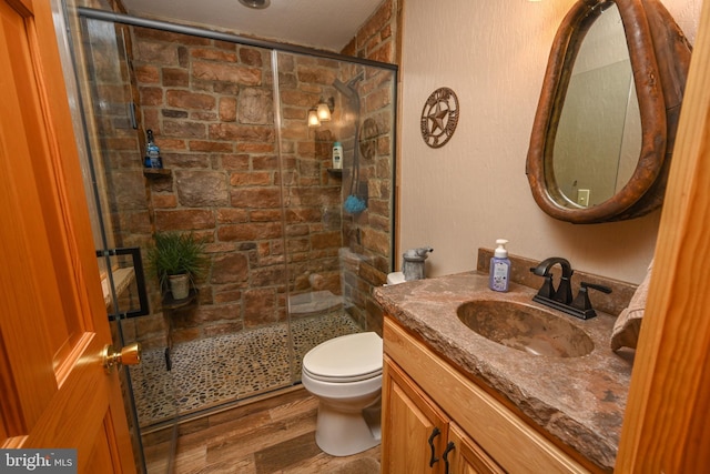 bathroom with wood-type flooring, toilet, a shower with shower door, and vanity