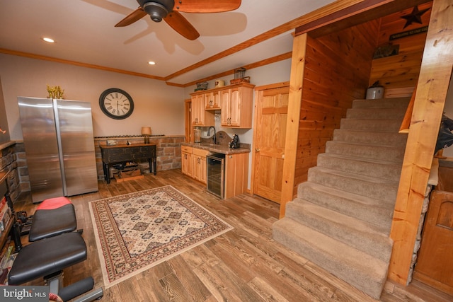 living room with hardwood / wood-style flooring, indoor wet bar, ceiling fan, ornamental molding, and beverage cooler