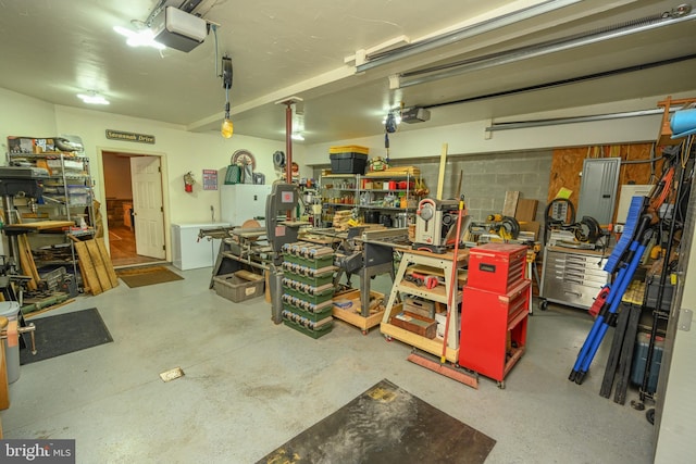 garage featuring a garage door opener, electric panel, and a workshop area