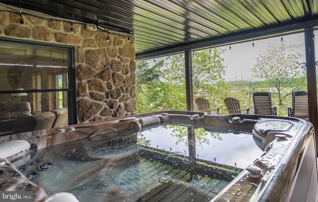 sunroom with a water view and a jacuzzi