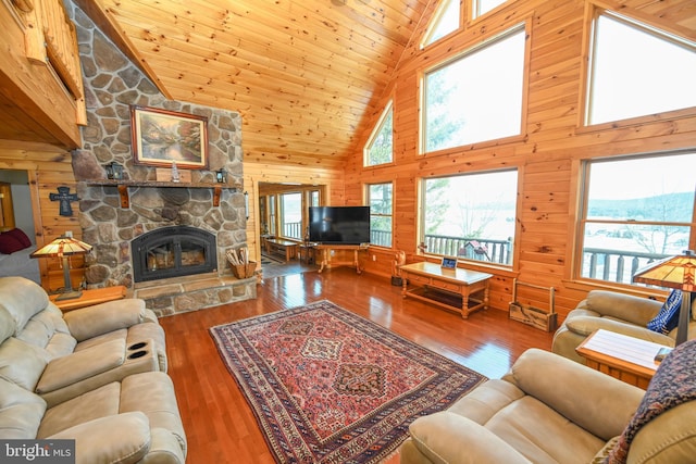 living room featuring a fireplace, wooden walls, wooden ceiling, and plenty of natural light