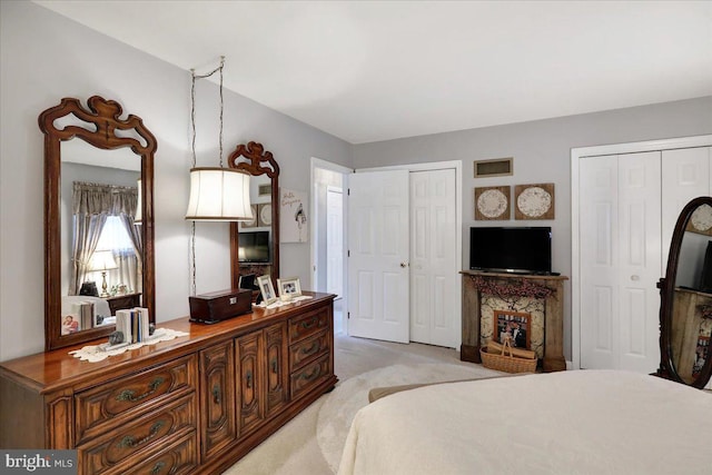 bedroom featuring multiple closets and light carpet