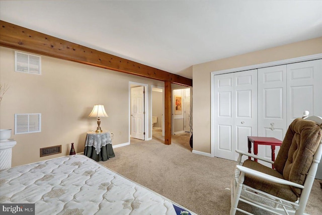 bedroom featuring connected bathroom, light colored carpet, a closet, and beamed ceiling