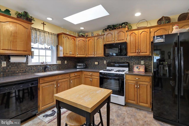 kitchen featuring sink, decorative backsplash, a skylight, and black appliances